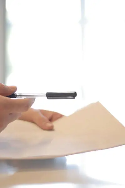 Firma de documentos legales en oficina con bolígrafo y papel.