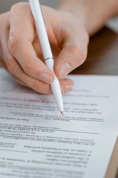Persona firmando un contrato de relevo con bolígrafo blanco.