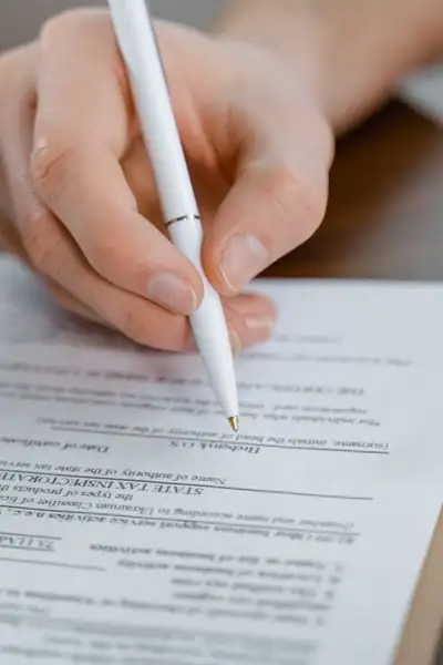 Persona firmando un contrato de relevo con bolígrafo blanco.
