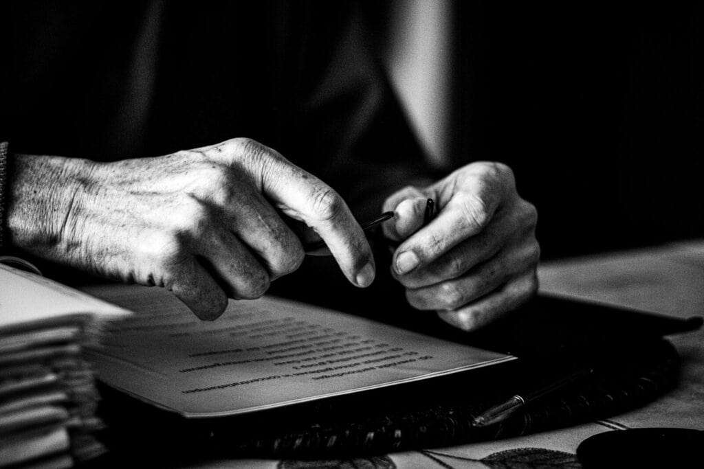 Manos firmando un documento legal en un entorno profesional.