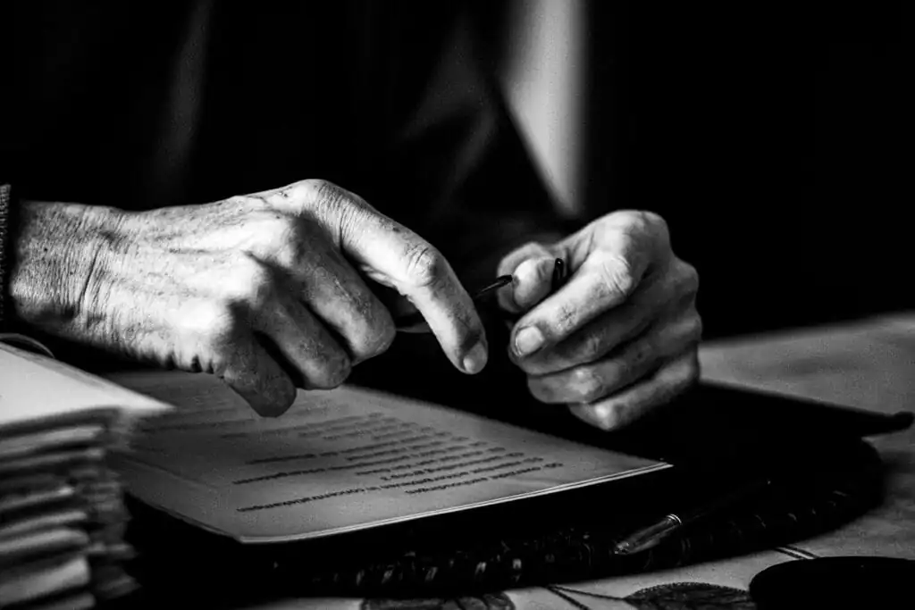 Manos firmando un documento legal en un entorno profesional.
