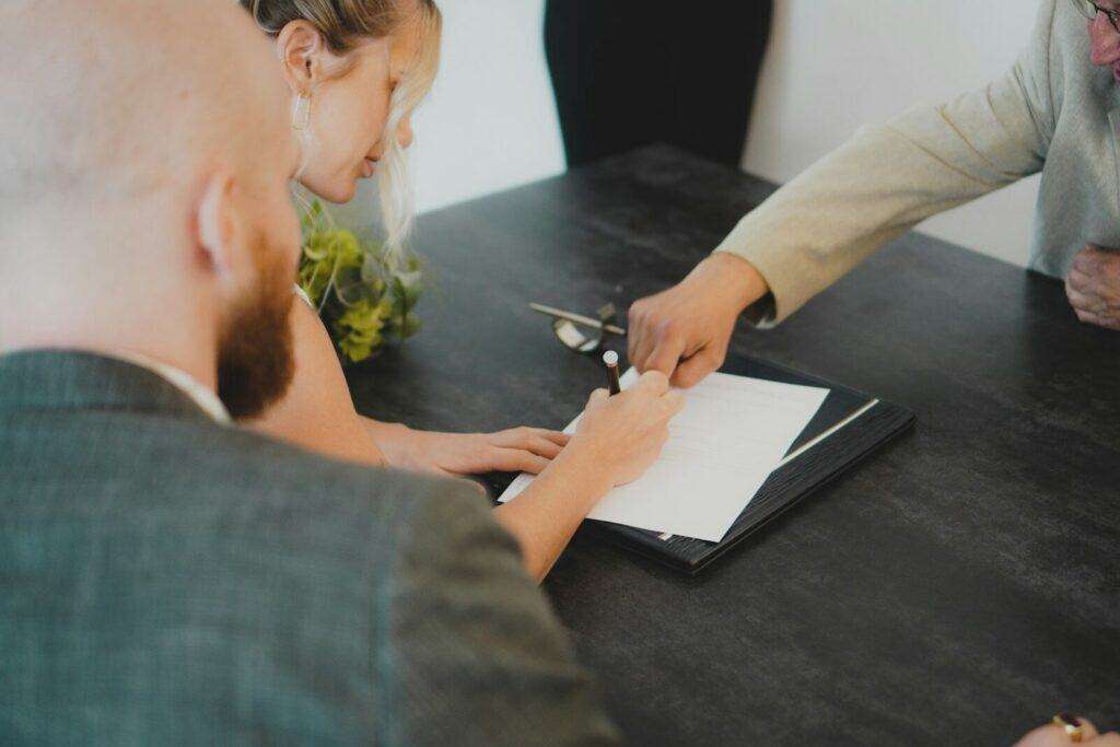 Personas firmando documentos legales en una reunión de herencia.