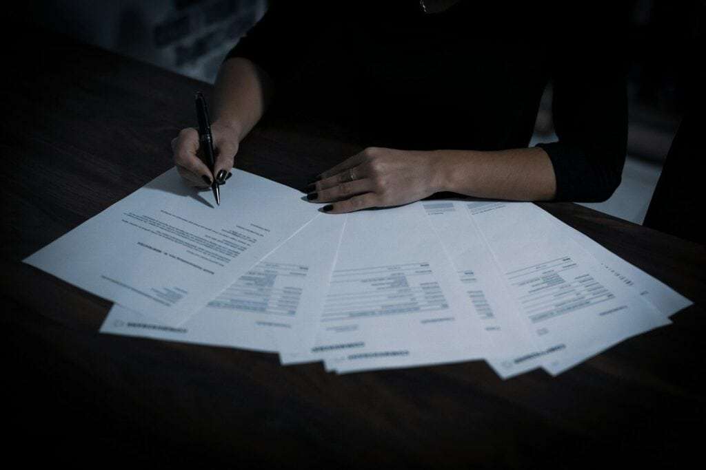 Persona firmando documentos legales de herencia y testamento.