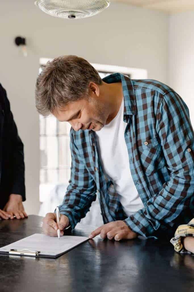 Hombre firmando contrato de alquiler en oficina moderna.